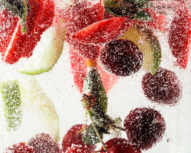 Vista cercana de limonada fría y fresca con hojas de menta cereza fresa y cubitos de hielo