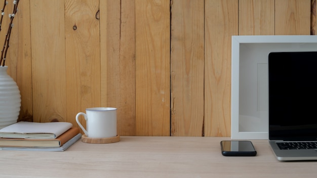 Vista cercana del lugar de trabajo con computadora portátil, teléfono inteligente, decoraciones y copia espacio en la mesa de madera