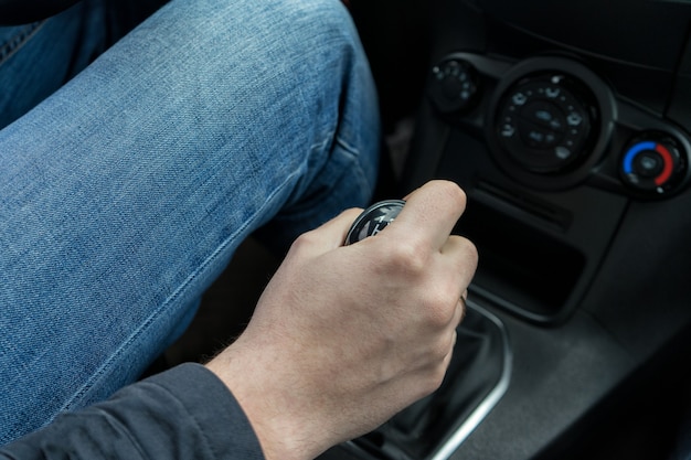 Vista cercana de la mano del hombre cambiando de marcha mientras conduce el coche