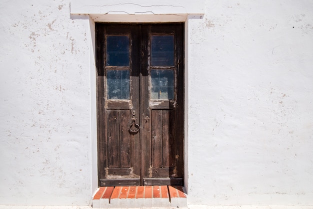 Vista cercana de una puerta de madera vieja de una casa blanca.