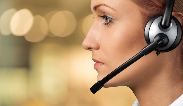 Vista cercana del rostro de mujer joven con auriculares, centro de llamadas o concepto de soporte