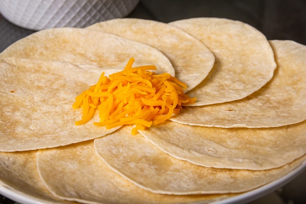 Foto vista cerrada de un plato de tacos blandos con queso encima