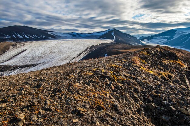 Vista desde la cima de la montaña hasta los picos nevados iluminados por los rayos del sol poniente