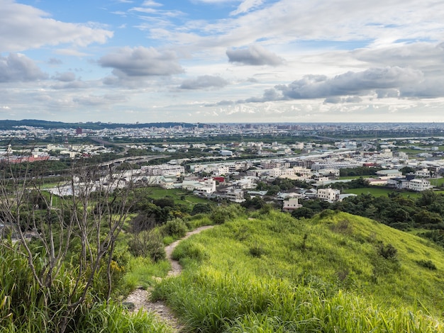 Vista de la ciudad desde la hermosa montaña. Cielo azul y prado verde en el atardecer.