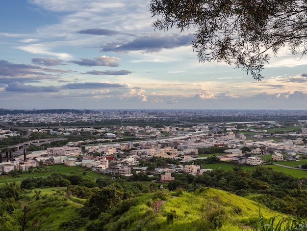 Vista de la ciudad desde la hermosa montaña. Cielo azul y prado verde en el atardecer.