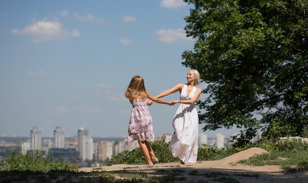 Vista de la ciudad. joven madre y su hija bailando en el parque.