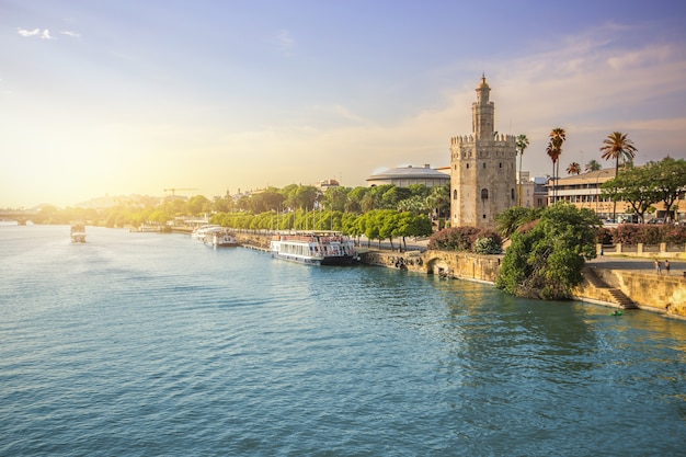 Vista de la ciudad de Sevilla y la torre del oro durante la puesta del sol con el equipo de piragüismo en el río