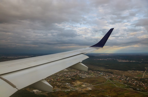 Foto vista de la ciudad desde una ventana de avión volando cielo azul, nubes ligeras de ala de avión