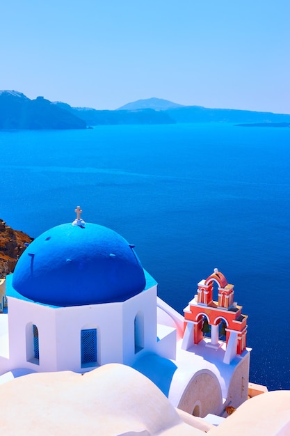 Vista com a igreja ortodoxa grega com cúpulas azuis e um pequeno campanário em Oia, na ilha de Santorini, Grécia