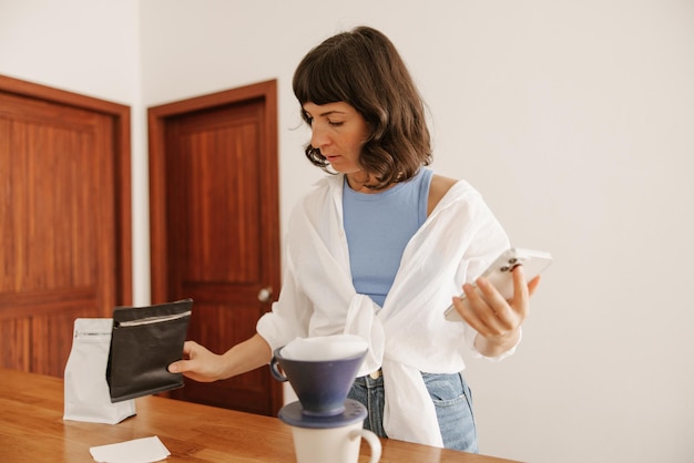 Vista completa de mujer con equipo de café y teléfono.