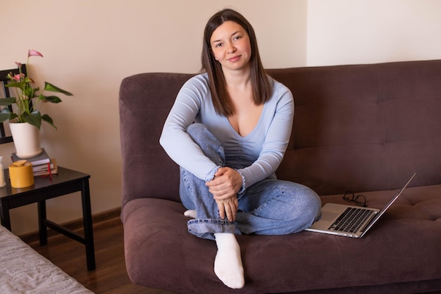 Vista completa de la mujer sentada en casa mira la cámara