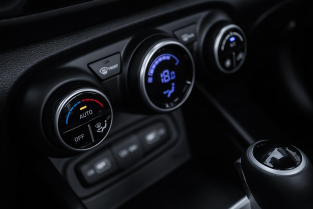 Vista de control de clima interior de coche negro con botón de aire acondicionado dentro de un coche