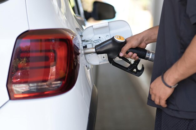 Vista cortada da mão do homem reabastecendo seu carro de luxo no posto de gasolina