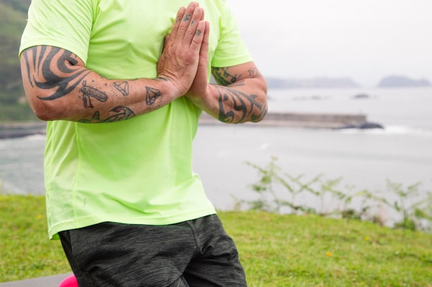 Vista cortada do homem moderno fazendo exercícios respiratórios com gesto de oração em ioga