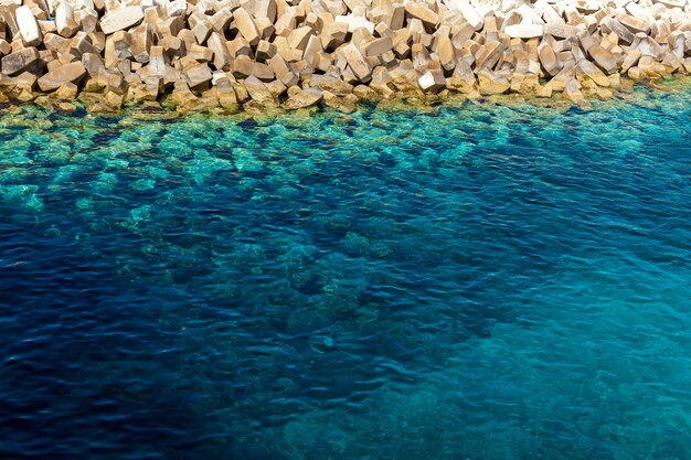 Una vista de la costa con pequeñas piedras y con agua azul pura. Una textura azul minimalista.