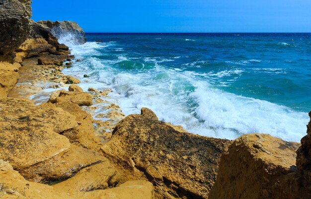 Vista de la costa rocosa del Atlántico de verano con salpicaduras de olas (afueras de Albufeira, Algarve, Portugal).