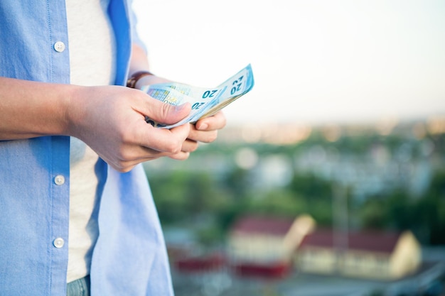Vista de cultivo de hombre contando billetes de dinero en efectivo desenfoque al aire libre espacio de copia