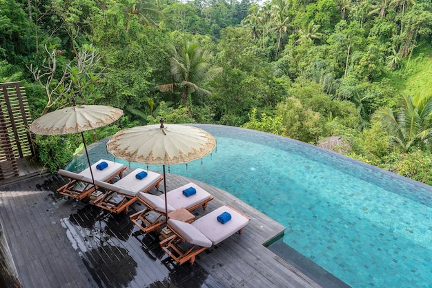 Vista da água da piscina e espreguiçadeiras na selva tropical perto de Ubud Bali Indonésia vista superior