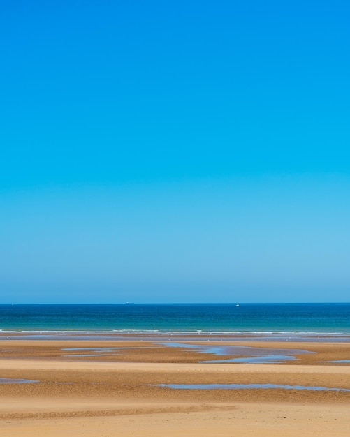 Vista da areia da praia com oceano e céu claro ao fundo