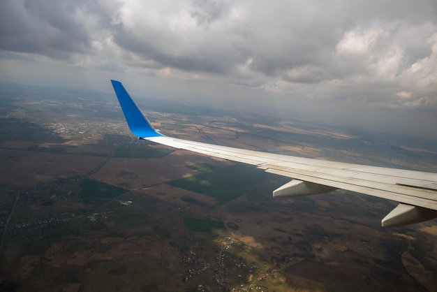 Vista da asa de avião a jato pousando no aeroporto com mau tempo. Conceito de viagens e transporte aéreo.