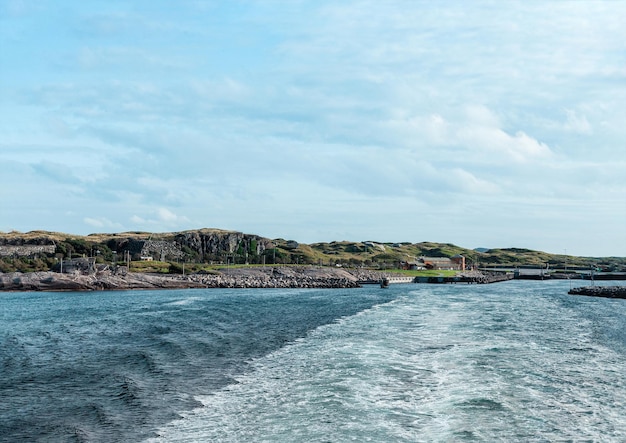 Vista da balsa na zona rural das colinas da Noruega com mar azul e céu