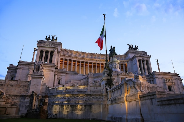 Vista da bandeira nacional italiana em frente ao Altare della Patria (Altar da Pátria), a escultura equestre de Victor Emmanuel