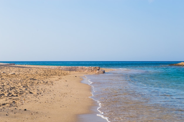 Vista da bela praia com água azul clara, areia dourada, barcos coloridos e montanhas. Paisagem de verão da Grécia e do mar Jónico.