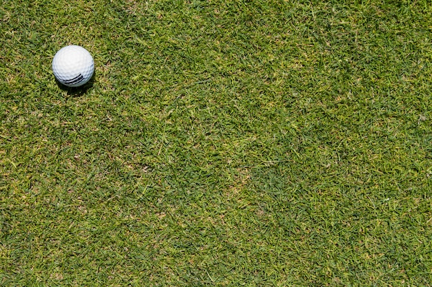 Vista da bola de golfe em um canto em um fundo da grama verde.