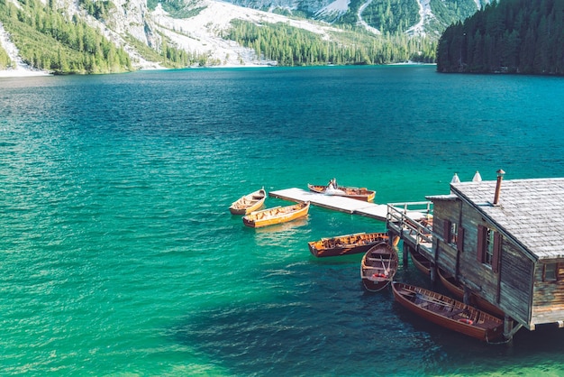 Vista da casa de madeira na água com cais e lago de barcos nas montanhas dolomitas