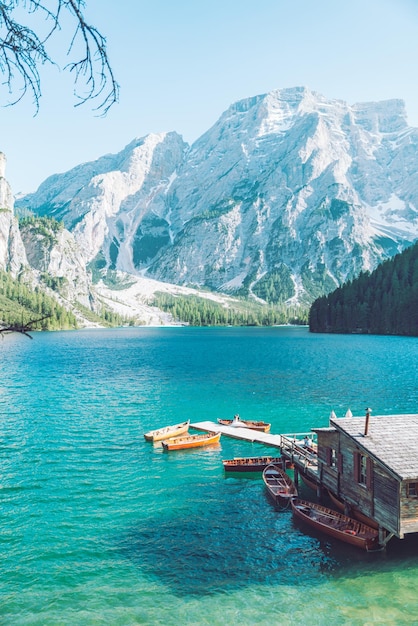 Vista da casa de madeira na água com cais e lago de barcos nas montanhas dolomitas