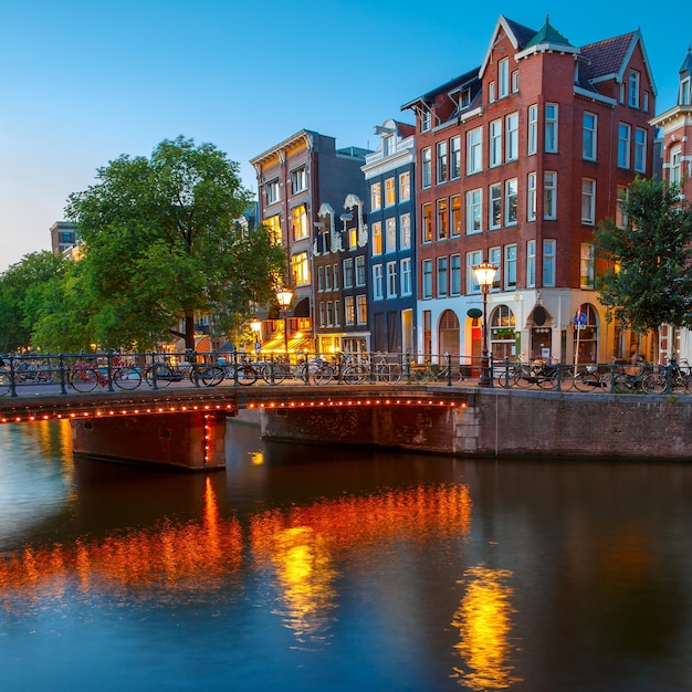 Vista da cidade à noite do canal de Amsterdã com casas holandesas