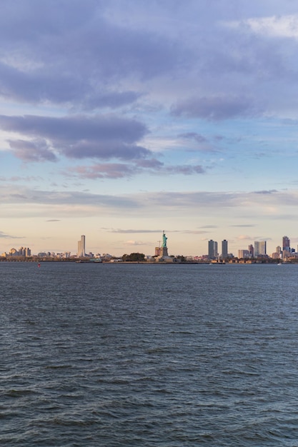 Vista da Estátua da Liberdade da água ao pôr do sol, Nova York, EUA