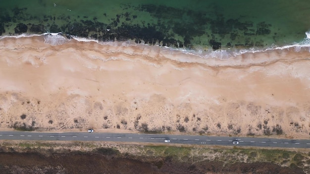 Vista da estrada ao longo da costa arenosa do mar a partir dos carros drone que conduzem na estrada ao longo do mar