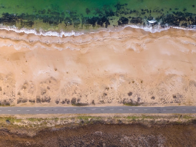 Vista da estrada ao longo da costa arenosa do mar a partir dos carros drone que conduzem na estrada ao longo do mar