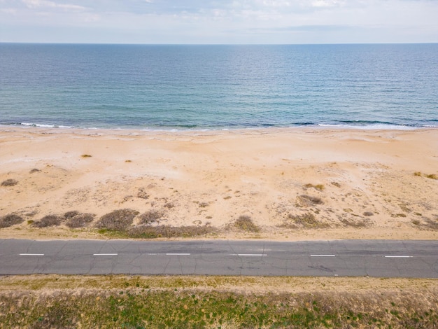 Vista da estrada ao longo da costa arenosa do mar a partir dos carros drone que conduzem na estrada ao longo do mar