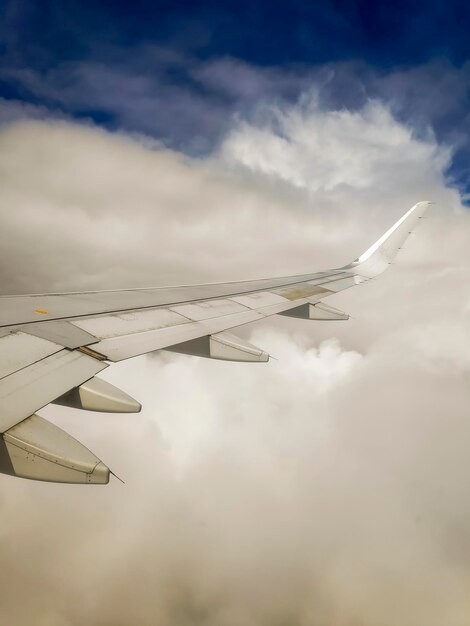 Vista da janela da asa de um avião voando sobre nuvens e um céu azul