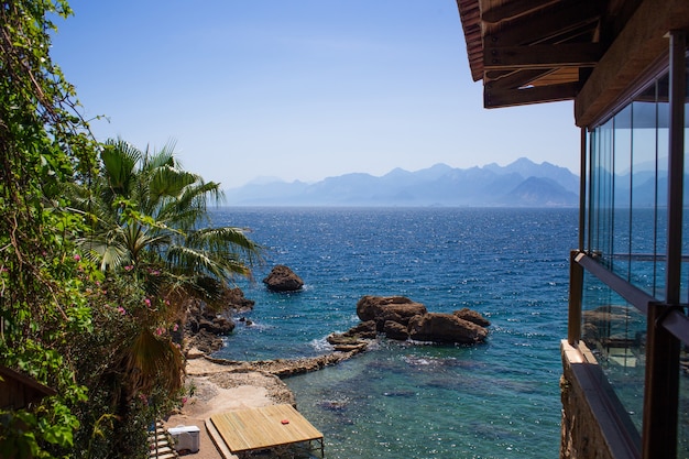 Vista da janela para as montanhas, mar, praia e palmeiras