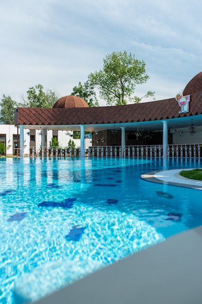 Vista da luxuosa piscina ao ar livre com águas azuis cristalinas e uma rotunda branca com pontes