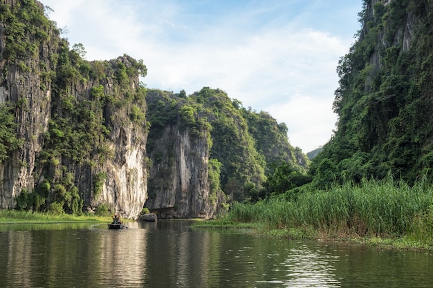 Vista da montanha de calcário no vale com cruzeiro turístico à noite, rio Ngo Dong, Ninh Binh, Baía de Halong em terra