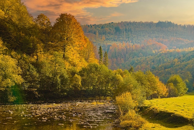 Vista da paisagem idílica do rio quando o sol está prestes a se pôr sobre a colina em um dia colorido de outono