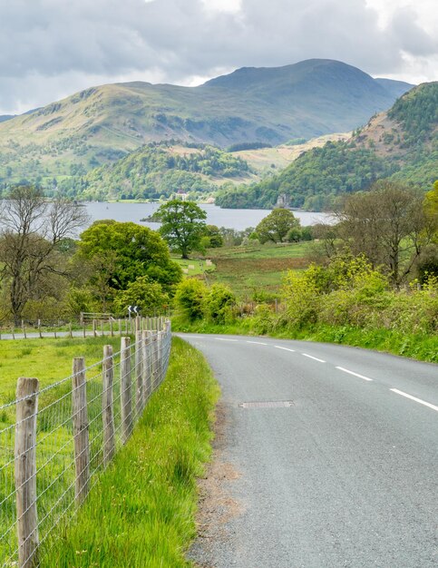 Vista da paisagem rural de árvores verdes e grama com montanha ao longo da estrada estreita na Inglaterra rural