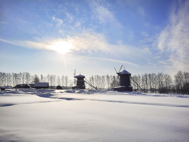 Vista da pequena aldeia de inverno com moinhos de vento e floresta