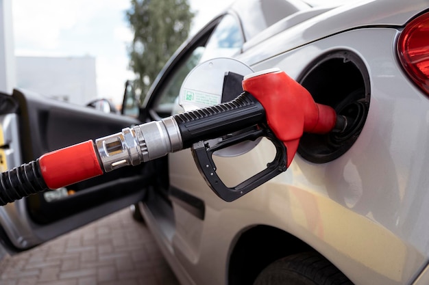 Foto vista da pistola de reabastecimento de combustível no pescoço do tanque de gasolina do carro reabastecendo o carro com combustível no posto de gasolina de pistola