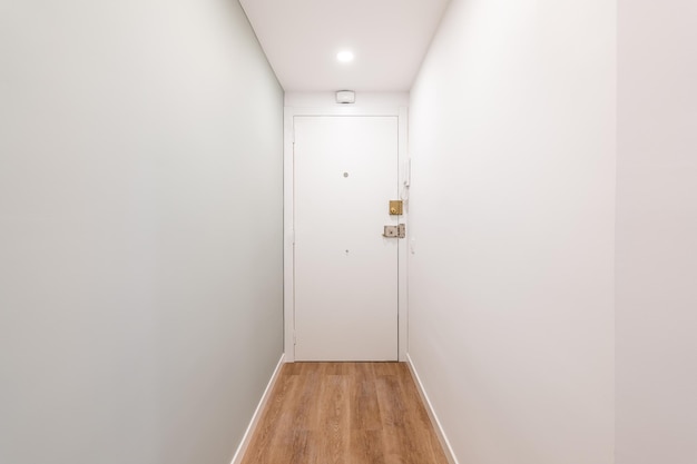 Vista da porta da frente em um corredor branco estreito e vazio em um hotel ou pequeno apartamento para uma pessoa