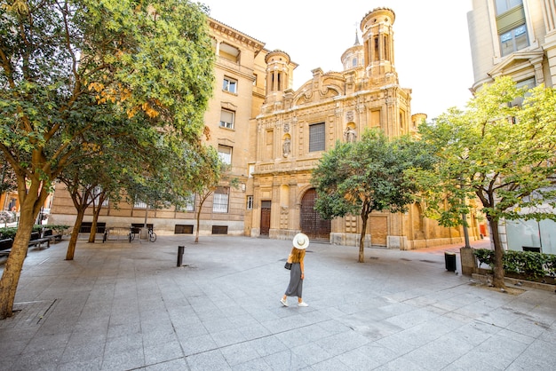 Vista da praça com a igreja de santa manteria e uma turista passeando na cidade de zaragoza, na espanha