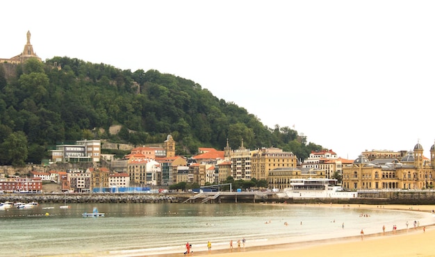 Foto vista da praia de areia, do oceano e da cidade em um dia de verão em são sebastião, espanha