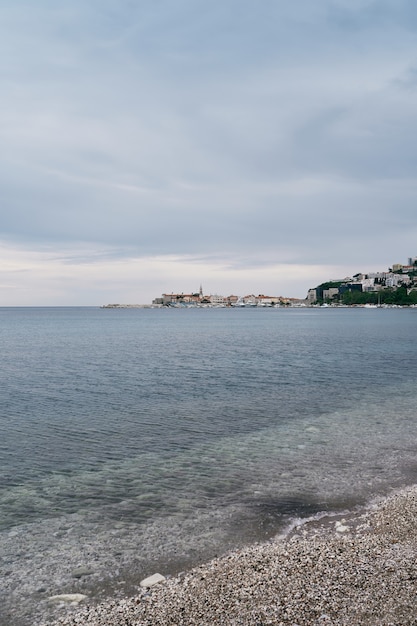 Vista da praia de cascalho para o mar, montanhas e edifícios