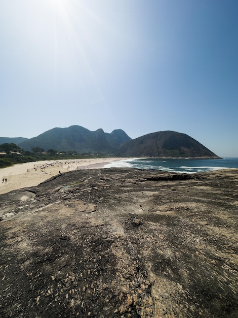 Vista da praia de itacoatiara em niterói, no rio de janeiro, brasil, com suas belas colinas ao redor das ondas grandes da praia em um dia ensolarado de verão