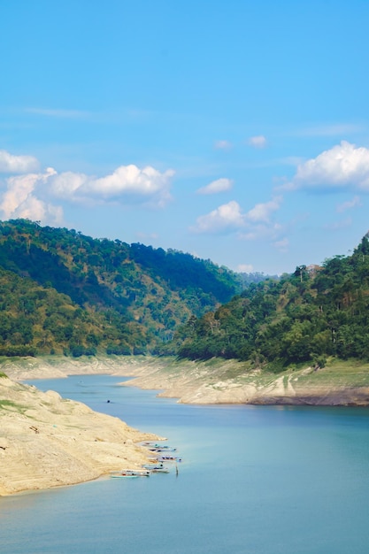 Vista da represa com água verde esmeralda Há montanhas verdes e céu brilhante