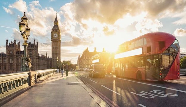 vista das casas do parlamento e do big ben com ônibus vermelho ao pôr do sol em londres. ideal para layouts de sites e revistas